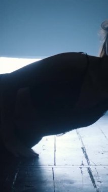 Mavi dumanla erotik dans eden seksi bir kızın silueti. Dikey video.