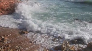 Deniz dalgaları taşların üzerinde yuvarlanıyor