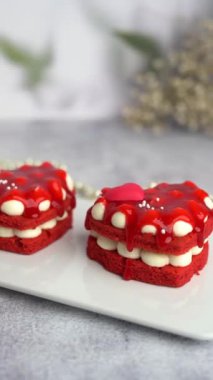 Gri arka planda çilek reçeli ile kaplanmış güzel kırmızı kalp şeklinde pasta. Dikey video.