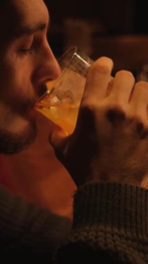 Bir gece barında genç bir adamın portresi. Bir adam kokteyl içer ve dinlenir. Dikey video.
