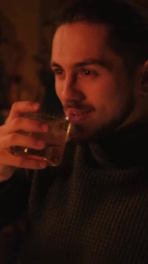 Bir gece barında genç bir adamın portresi. Bir adam kokteyl içer ve dinlenir. Dikey video.