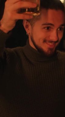 Bir gece barında genç bir adamın portresi. Bir adam kokteyl içer ve dinlenir. Dikey video.