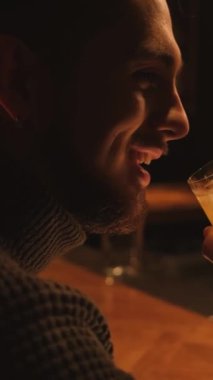 Bir gece barında genç bir adamın portresi. Bir adam kokteyl içer ve dinlenir. Dikey video.