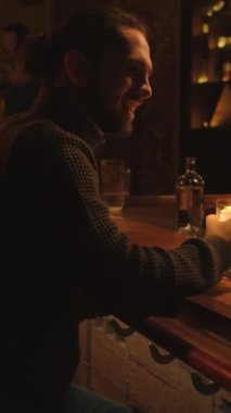 Bir gece barında genç bir adamın portresi. Bir adam kokteyl içer ve dinlenir. Dikey video.