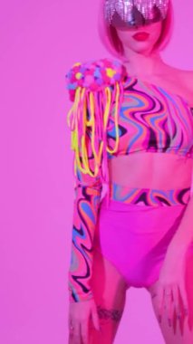 Yaratıcı gözlüklü ve neon ışıklı bir kadın güzel dans eder. Pembe moda neon ışık. Dikey video.