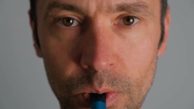 Elektronik sigara içen ve nefes veren bir adamın yakın çekimi..