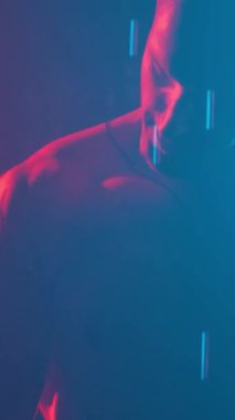 Young muscular guy in the studio with new lights and smoke. Vertical video.