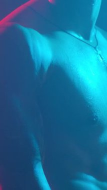 Young muscular guy in the studio with new lights and smoke. Vertical video.