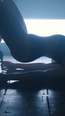 Mavi dumanla erotik dans eden seksi bir kızın silueti. Dikey video.