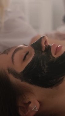 Genç ve güzel bir kızın yüzünün karbonu soyuluyor. Cilt bakımı kozmetolojisi. Lazer terapisi ve cilt tedavisi. Dikey video.