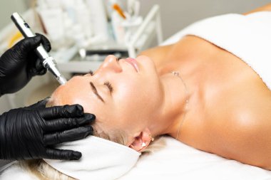 Mikroedle RF kaldırma prosedürü. Bir kozmetikçi bir kadına yüz gençleştirme ameliyatı yapar. Donanım kozmetolojisi.