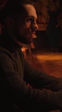 Bir gece barında genç bir adamın portresi. Bir adam kokteyl içer ve barmenle iletişim kurar. Dikey video.