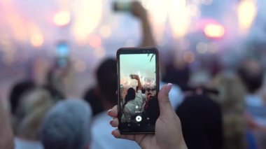 Bir kız sokak festivalinde cep telefonuyla fotoğraf çekiyor..
