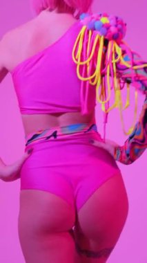 Yaratıcı gözlüklü ve neon ışıklı bir kadın güzel dans eder. Pembe moda neon ışık. Dikey video.