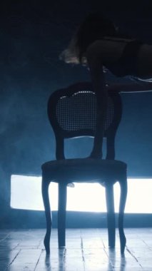 Mavi dumanla erotik dans eden seksi bir kızın silueti. Dikey video.