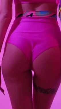 Yaratıcı gözlüklü ve neon ışıklı bir kadın güzel dans eder. Pembe moda neon ışık. Dikey video.