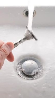 Lavaboda tıraş bıçağı temizliyorum. Tıraş bıçağını suyla yıkıyorum. Dikey video.