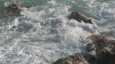 Deniz dalgaları taşların üzerinde yuvarlanıyor