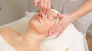 Kadın 50-60 yaşları arasında kaplıca salonunda cilt bakımı görüyor. Güzellik uzmanı mankenlerin yüzleriyle ilgilenir..