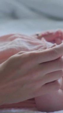 Genç anne, emziren küçük bir çocuğun bacağını öpüyor. Dikey video.