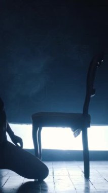 Mavi dumanla erotik dans eden seksi bir kızın silueti. Dikey video.