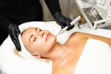 Mikroedle RF kaldırma prosedürü. Bir kozmetikçi bir kadına yüz gençleştirme ameliyatı yapar. Donanım kozmetolojisi.