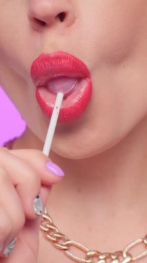 Kırmızı dudaklı, alımlı, genç ve güzel bir manken. Eşofmanlı, şeker yalayan pop kızı yiyor. Dikey video