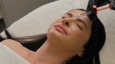 Kadın çenesi yakınındaki şırınga, çene şekli düzeltmesi için doldurulmuş güzellik iğneleri..