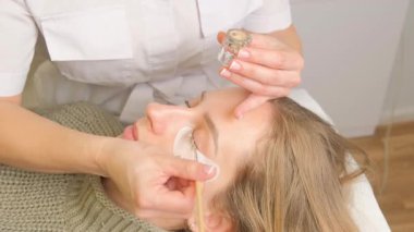 Güzellik salonunda kirpik boyama prosedürü. Modellerin göz kapakları, kirpikleri boyama süreci.