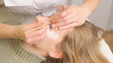 Güzellik salonunda kirpik boyama prosedürü. Modellerin göz kapakları, kirpikleri boyama süreci.