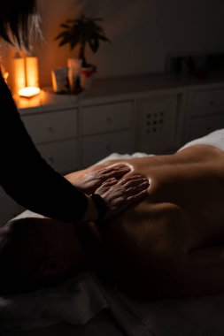 Kadın masöz, spa salonundaki adama profesyonel sırt masajı yapıyor..