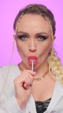 Kırmızı dudaklı, alımlı, genç ve güzel bir manken. Eşofmanlı, şeker yalayan pop kızı yiyor. Dikey video