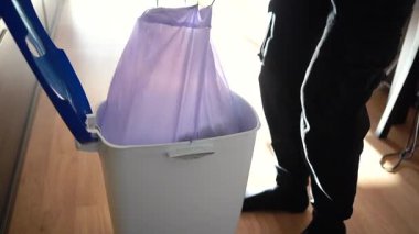 Adamın biri çöp torbasını çöpten çıkarıyor. Temizliği ve ev temizliğini sürdürmek.