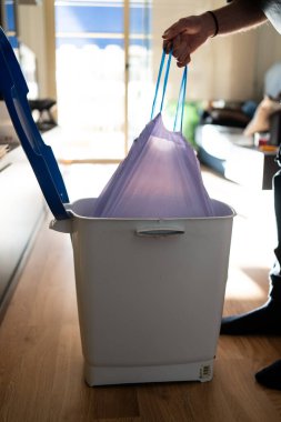 Adamın biri çöp torbasını çöpten çıkarıyor. Temizliği ve ev temizliğini sürdürmek.