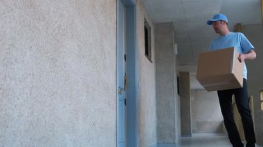 Teslimatçı, kapısında modern bir teslimat hizmeti sunan bir müşteriye kutuyu teslim eder..