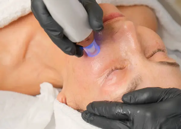 Güzellik uzmanının cilt bakımı sırasında güzel bir kadının yakın plan portresi..