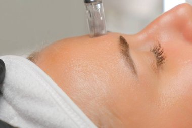 Mikroedle RF kaldırma prosedürü. Bir kozmetikçi bir kadına yüz gençleştirme ameliyatı yapar. Donanım kozmetolojisi.