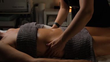 Profesyonel bir terapist rahatlatıcı bir spa ortamında hindistan cevizi kabuğu kullanarak karın masajı yapar..