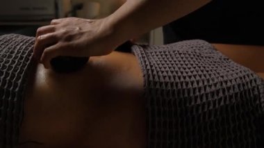 Profesyonel bir terapist rahatlatıcı bir spa ortamında hindistan cevizi kabuğu kullanarak karın masajı yapar..