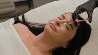 Kadın çenesi yakınındaki şırınga, çene şekli düzeltmesi için doldurulmuş güzellik iğneleri..