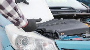 Otomobil servisinde kullanılmış araba hava filtresinin elle değiştirilmesi