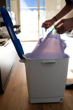 Adamın biri çöp torbasını çöpten çıkarıyor. Temizliği ve ev temizliğini sürdürmek.