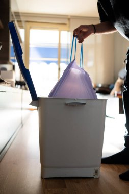Adamın biri çöp torbasını çöpten çıkarıyor. Temizliği ve ev temizliğini sürdürmek.