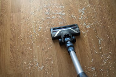 Elektrikli süpürge hortumu dağınık pirinç tanelerini ahşap zemin temizleme, dağınıklık ve ev bakımı konseptinden topluyor..