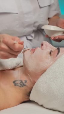 Bir kadın kaplıcada yüz maskesi tedavisinden zevk alır, bir güzellik uzmanının fırçasıyla uygulanır..