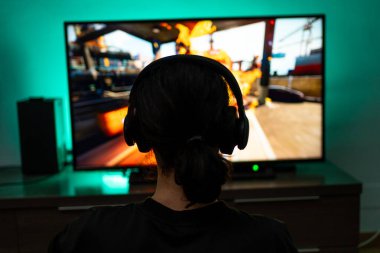 Kulaklık takan genç oyuncu konsolun arka planında oynuyor..