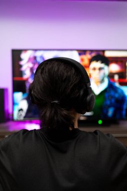 Kulaklık takan genç oyuncu konsolun arka planında oynuyor..