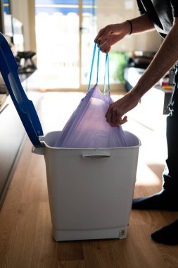 Adamın biri çöp torbasını çöpten çıkarıyor. Temizliği ve ev temizliğini sürdürmek.