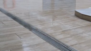 Kapalı hava kanalizasyon ızgarası. Yağmurdan sonra fayanslı yüzeyde su birikintisi var..