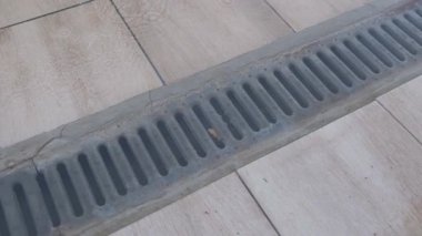 Kapalı hava kanalizasyon ızgarası. Yağmurdan sonra fayanslı yüzeyde su birikintisi var..